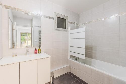 une salle de bain blanche avec une baignoire et un lavabo dans l'établissement Beautiful 4P Apartment with Garden - Paris 16th, à Paris