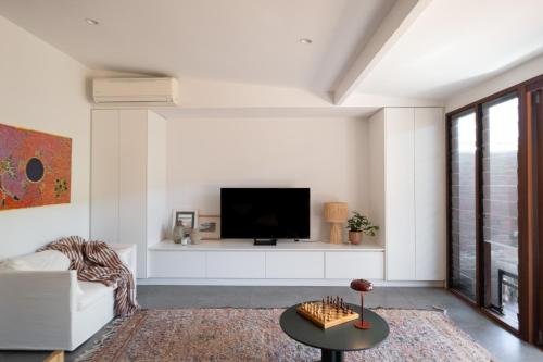 a living room with a tv on a white wall at Traveller's Return Retreat in Fremantle