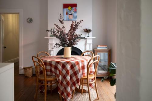 a dining room table with a vase of flowers on it at Traveller's Return Retreat in Fremantle