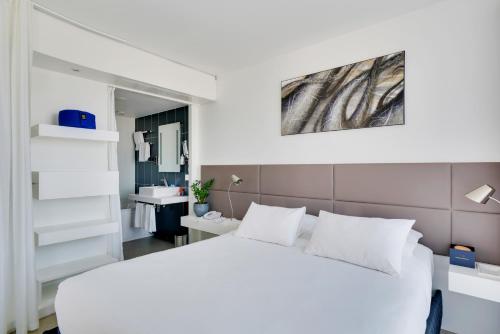 a bedroom with a white bed and a bathroom at Novotel Suites Paris Issy Les Moulineaux in Issy-les-Moulineaux