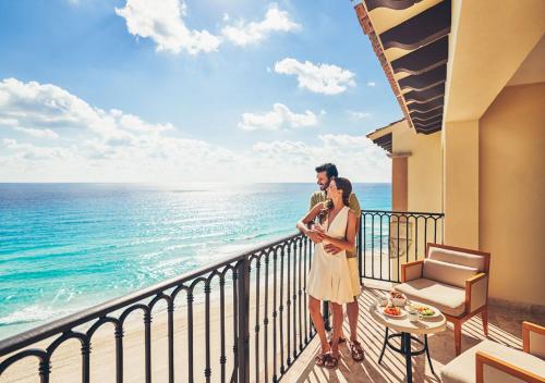a man and woman standing on a balcony looking at the ocean at Grand Park Royal Cancun - All Inclusive in Cancún