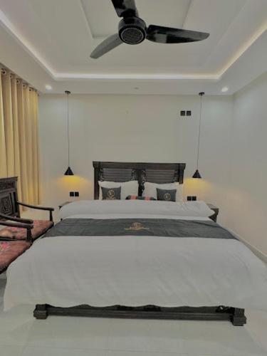 a bedroom with a white bed with a ceiling fan at Kuwait Continental Hotel Bahrain by Khan Familia Travels in Kalām