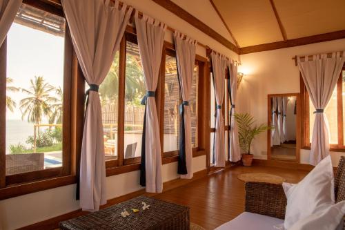 a room with windows and a bed and a table at Pole Pole Bungalows in Utende