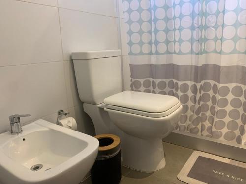 a bathroom with a toilet and a sink and a shower curtain at Vista24uy Ref1003 in Bella Vista