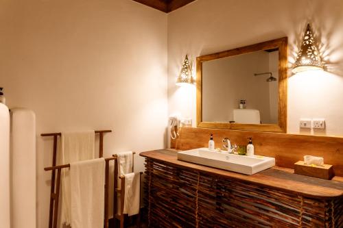 a bathroom with a sink and a mirror and towels at Pole Pole Bungalows in Utende