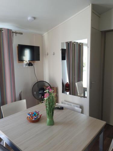 a dining room table with a vase of flowers on it at Mobil Home Ohana Camping du Ried in Boofzheim
