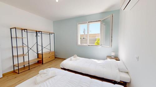 Dos camas en una habitación con ventana. en La Petite Vague, en Saint Gilles Croix de vie
