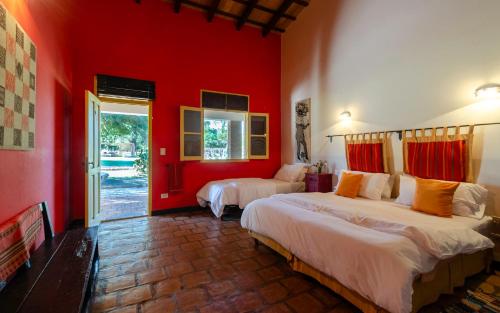 a bedroom with two beds and a red wall at La Vaca Tranquila in San Carlos