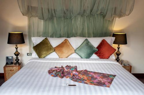 a white bed with colorful pillows on it at Tango Luxe Beach Villa, Koh Samui in Choeng Mon Beach