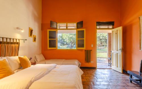a bedroom with two beds and an orange wall at La Vaca Tranquila in San Carlos