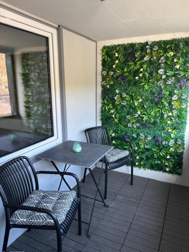 a table and chairs on a patio with a green wall at Home Ida in Klotten