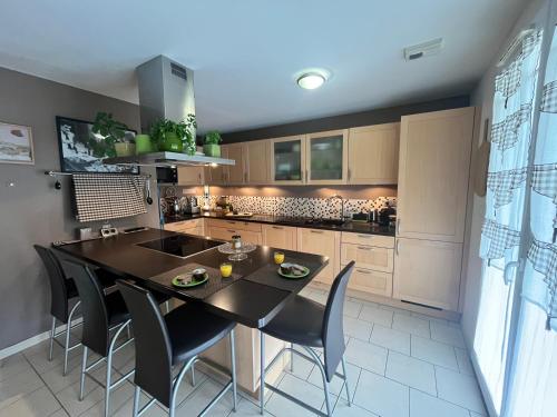 une cuisine avec une table noire et des chaises dans l'établissement Villa Familiale Soleil et détente, à Salignac