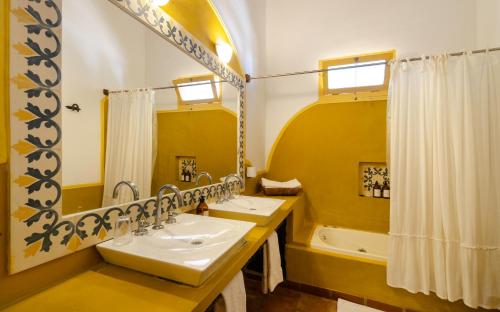 a yellow bathroom with two sinks and a tub at La Vaca Tranquila in San Carlos