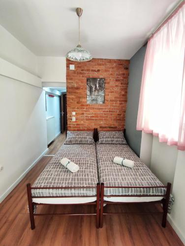 a bed in a room with a brick wall at Hostel Temza in Zagreb