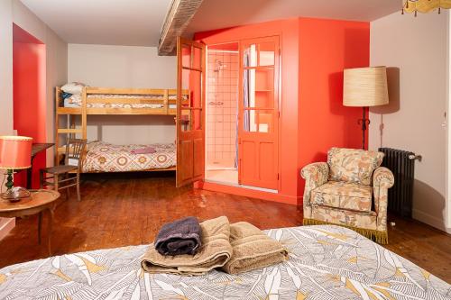 a bedroom with orange walls and a bed and a chair at C'est Chouette le gîte ! in Saint-Jodard