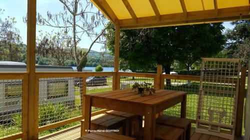 une table en bois sur une terrasse avec une clôture dans l'établissement Camping le Calatrin - Onlycamp, à Paladru