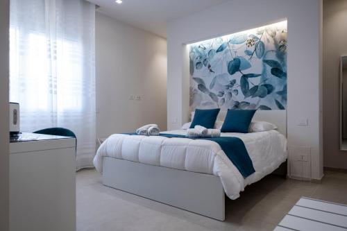 a white bedroom with a large bed with blue pillows at Villa Kora Suites&Pool in San Leone
