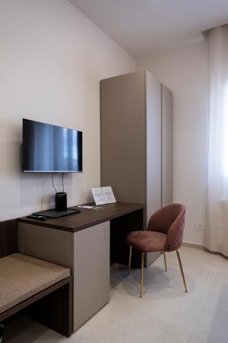 a desk with a television and a chair in a room at Villa Kora Suites&Pool in San Leone