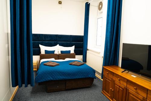 a bedroom with a bed with blue curtains and a tv at Penzión Oliver Humenné in Humenné