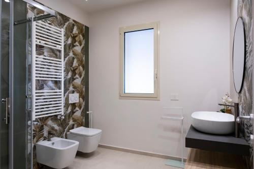 a bathroom with a sink and a toilet and a mirror at Villa Kora Suites&Pool in San Leone