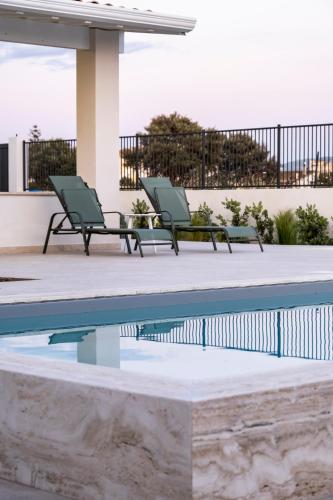 two green chairs sitting next to a swimming pool at Villa Kora Suites&Pool in San Leone