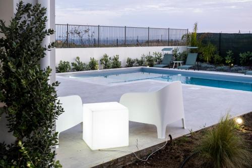 a swimming pool with white furniture next to a white house at Villa Kora Suites&Pool in San Leone