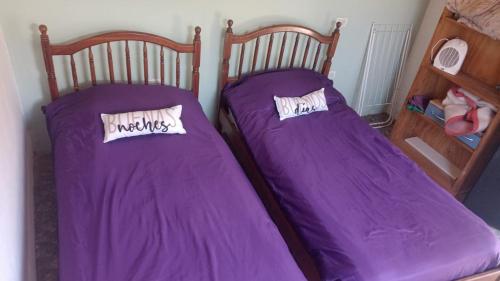 two beds in a room with purple sheets and pillows at Vista los Andes in Cacheuta