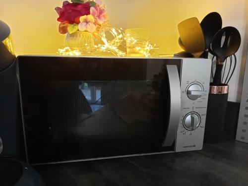 a microwave on a table with a vase of flowers at Fully equipped studio in Saint-Germain-de-Joux
