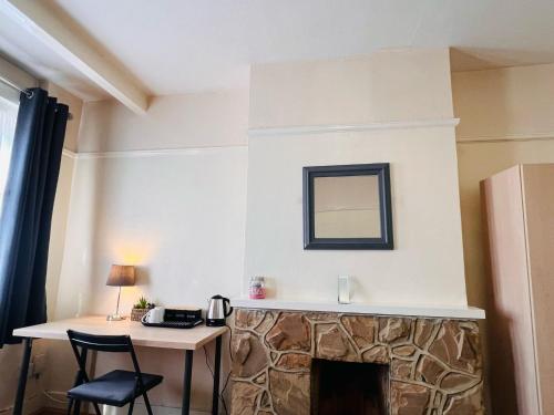 a room with a fireplace with a table and a mirror at Cosy Double Room in Harrow & Wealdstone - Desk,Fast Free Wi-Fi,Near Station - 15 mins by train to Wembley Central & Euston in Harrow Weald