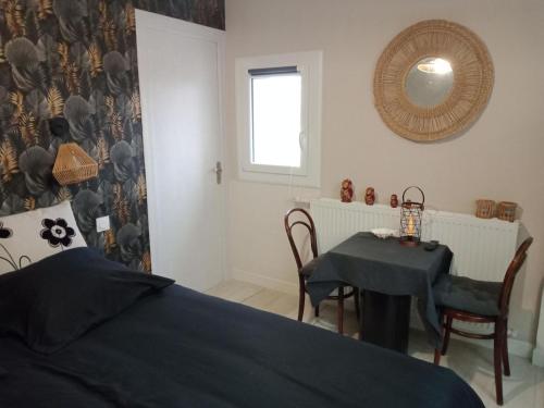 a bedroom with a bed and a table and a mirror at La Maison in Mirebeau-sur-Bèze