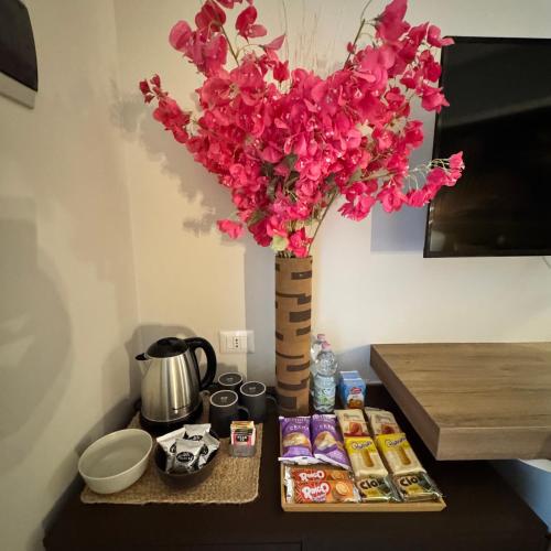 a vase filled with pink flowers on a table at Namuri Rooms in Giardini Naxos