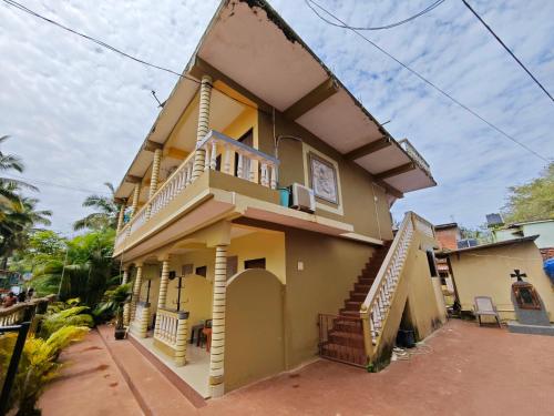 a yellow house with stairs on the side of it at Regina Residency in Patnem