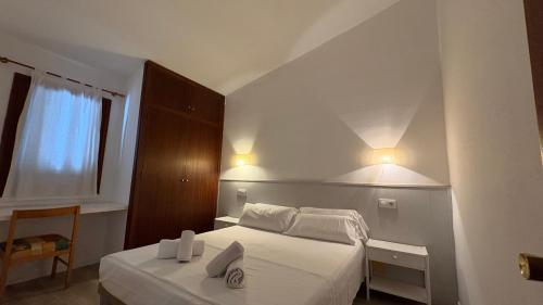 a white bedroom with a bed and a window at Villas Las Alondras in Cala en Forcat