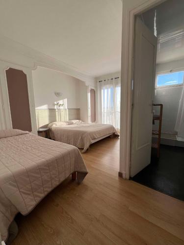 une chambre d'hôtel avec deux lits et une fenêtre dans l'établissement Le Canetois, à Canet