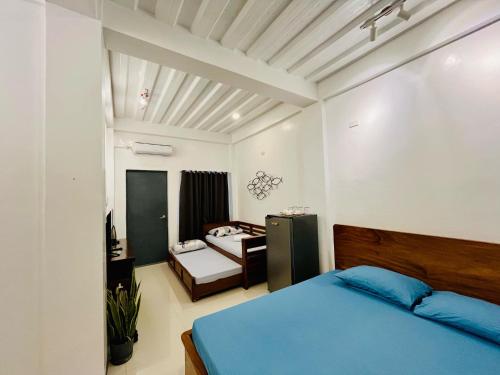 um quarto com uma cama azul e uma mesa em FN Lodge - town proper em Palompon