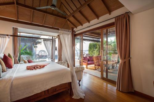 a bedroom with a bed and a sliding glass door at Tango Luxe Beach Villa, Koh Samui in Choeng Mon Beach