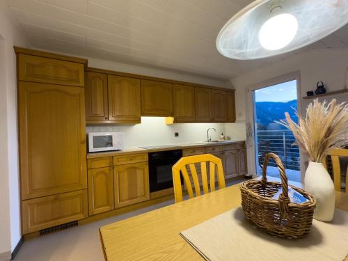 a kitchen with wooden cabinets and a table with a basket at Apartment Rosengarten - Rosenheim Apartments in Tires