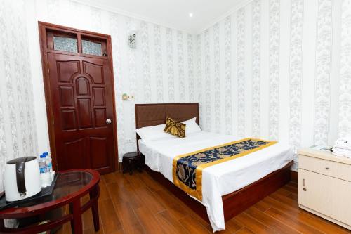 a bedroom with a bed and a table and a door at Nhà nghỉ Đức Trọng in Móng Cái