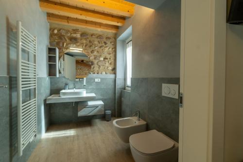 Un baño con inodoro, lavabo y espejo. en La Casa in Paese, en Peschiera del Garda