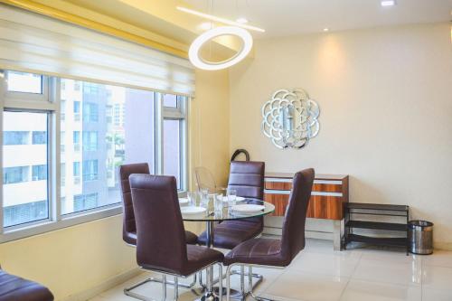 a dining room with a table and chairs and a window at Metro Luxe Stay Near DOJ Embassy and St Lukes in Manila