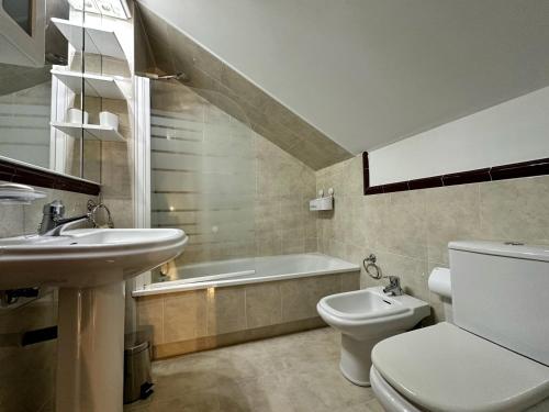 a bathroom with a sink and a toilet and a bath tub at Villa de Pedrena - 32801 in Pedreña