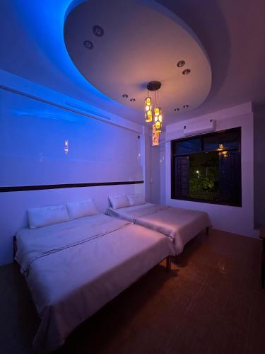two beds in a room with a blue lighting at Cali homestay in Phú Vang