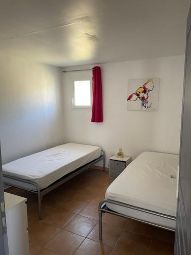 two beds in a small room with a window at Gîte La Durande in Venterol