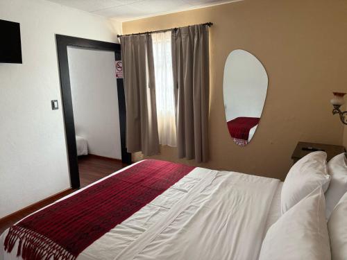 a bedroom with a large bed and a mirror at Hotel El Morlaco in Cuenca
