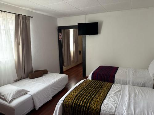 a hotel room with two beds and a flat screen tv at Hotel El Morlaco in Cuenca