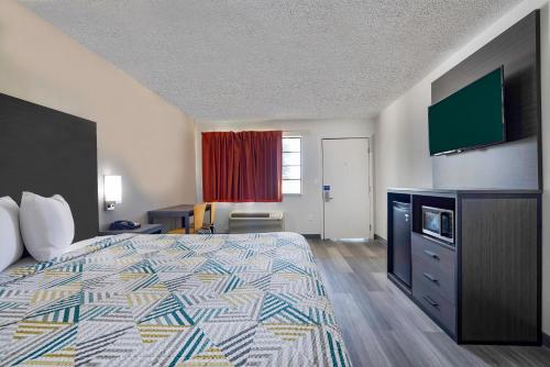 a hotel room with a bed and a flat screen tv at Motel 6 Lake Charles, LA in Lake Charles