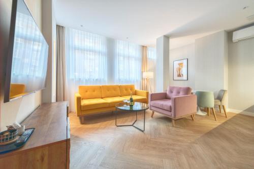 a living room with a yellow couch and two chairs at Retro Boutique by NorthSide Apartments in Gdańsk