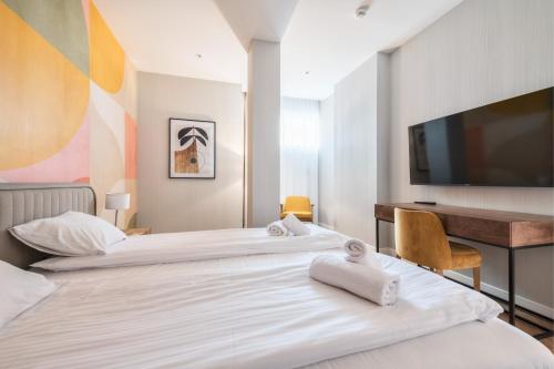 two beds in a room with a desk and a television at Retro Boutique by NorthSide Apartments in Gdańsk