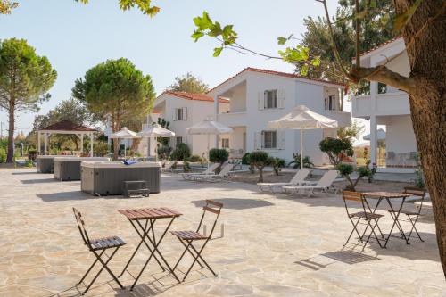 a courtyard with chairs and tables and umbrellas at Naftilos Rosmarinus Apartments in Potokáki