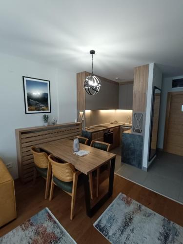 a living room with a wooden table and a kitchen at Apartmani Trg Zlatibor in Zlatibor
